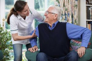 Older adult and family member reviewing a daily care checklist at a kitchen table.